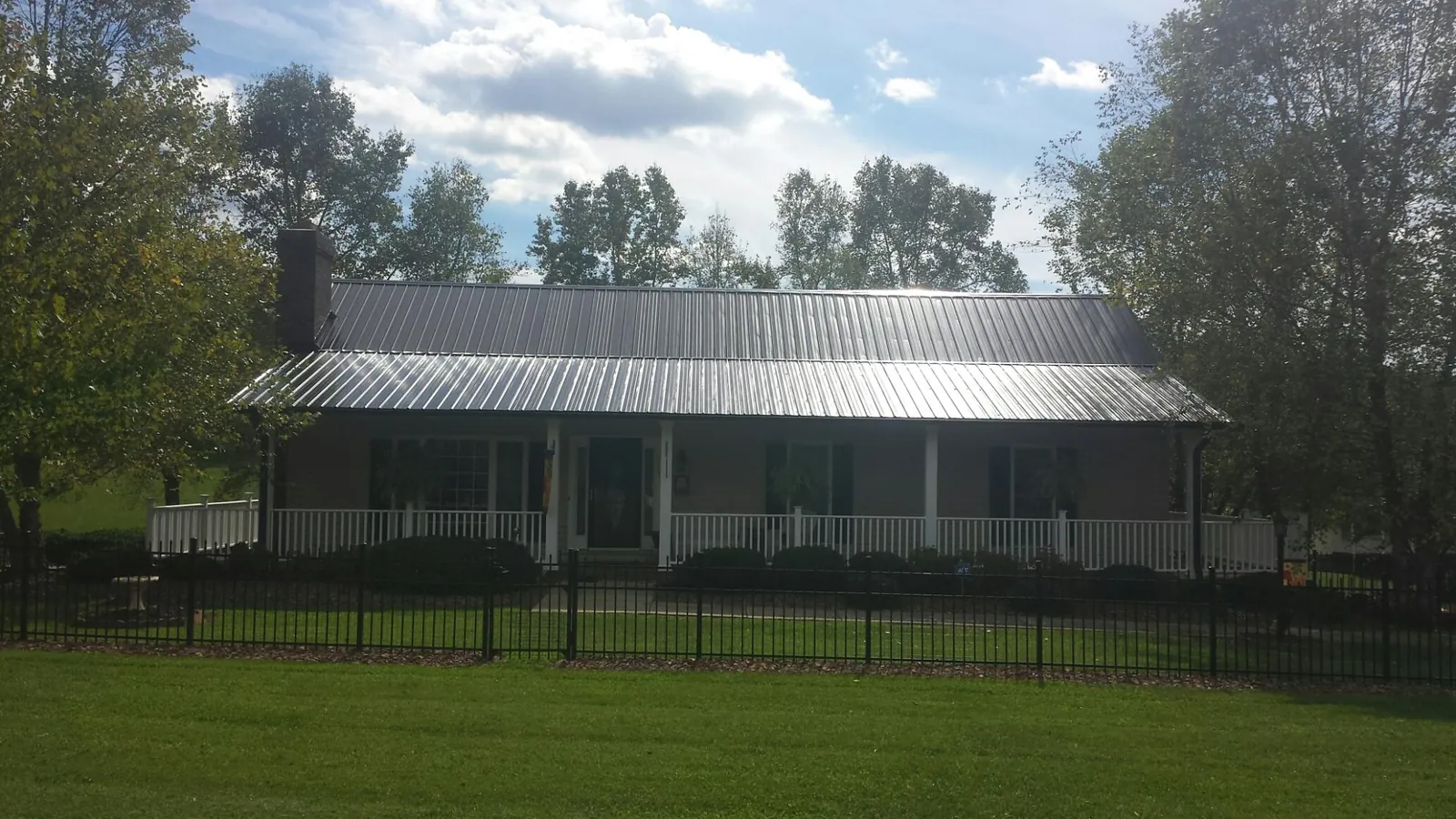 Gray metal roof on a brick ranch with a full width front porch — Gutter Guard Installation work by our crew in Conner